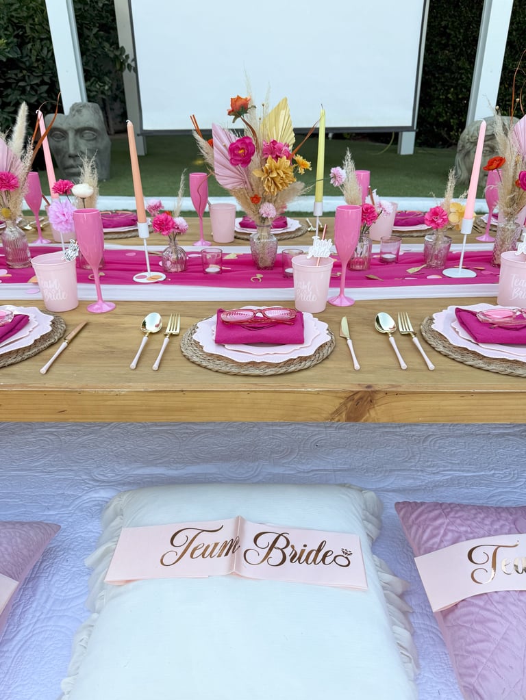 Elegant bridal shower table setup with pink and white decor, floral arrangements, and Team Bride pillow in foreground
