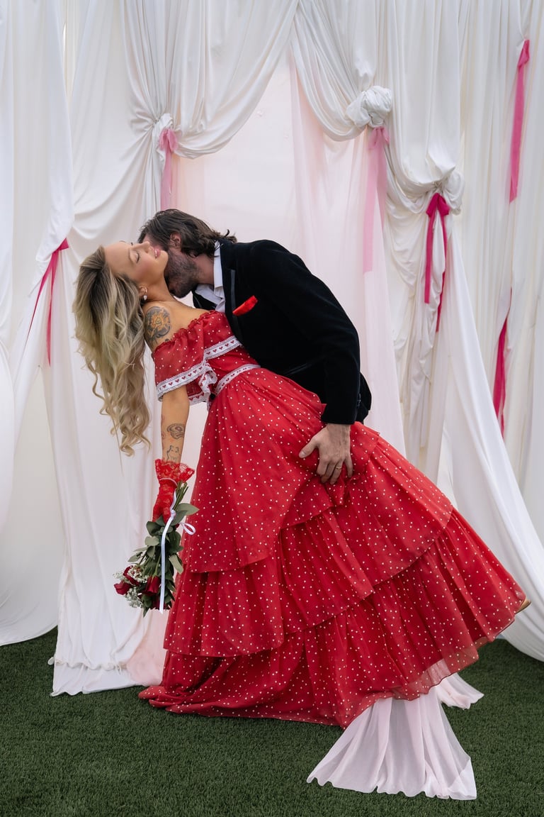 Couple kissing beneath draped white and pink fabric