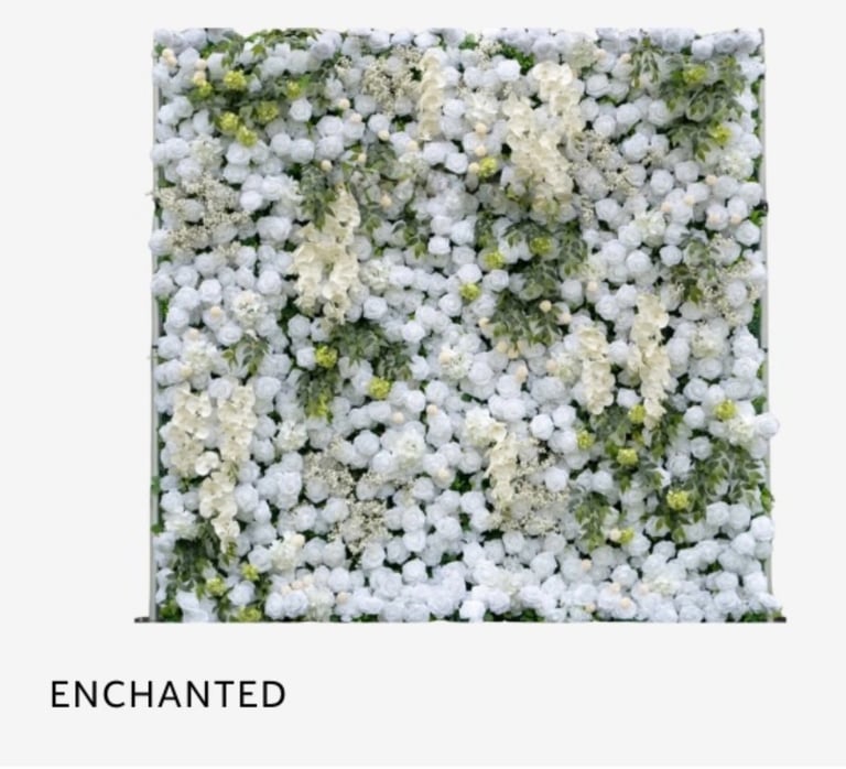 Dense white flower wall arrangement with green foliage labeled Enchanted