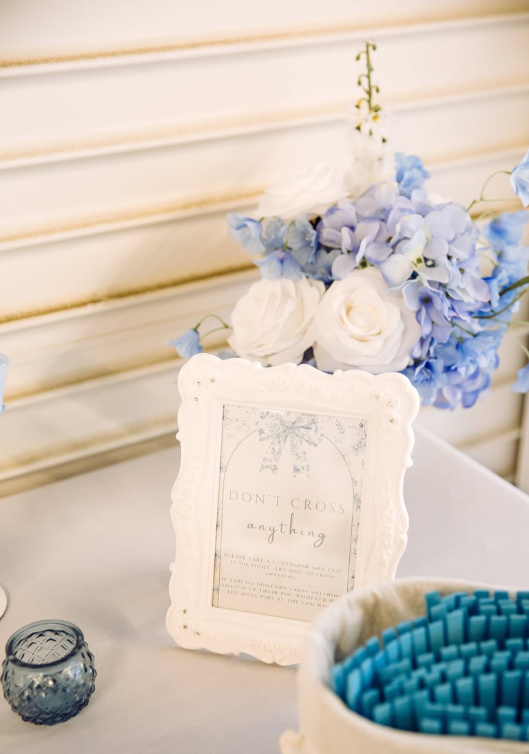 White decorative frame with text beside blue and white flower arrangement on table