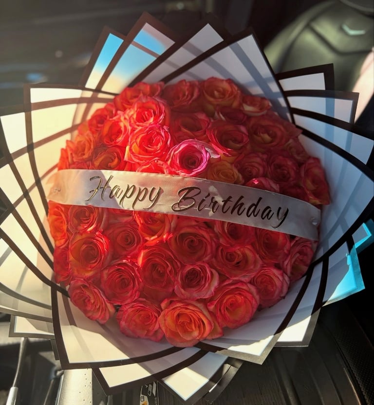Round bouquet of red roses with Happy Birthday ribbon banner, wrapped in geometric patterned paper