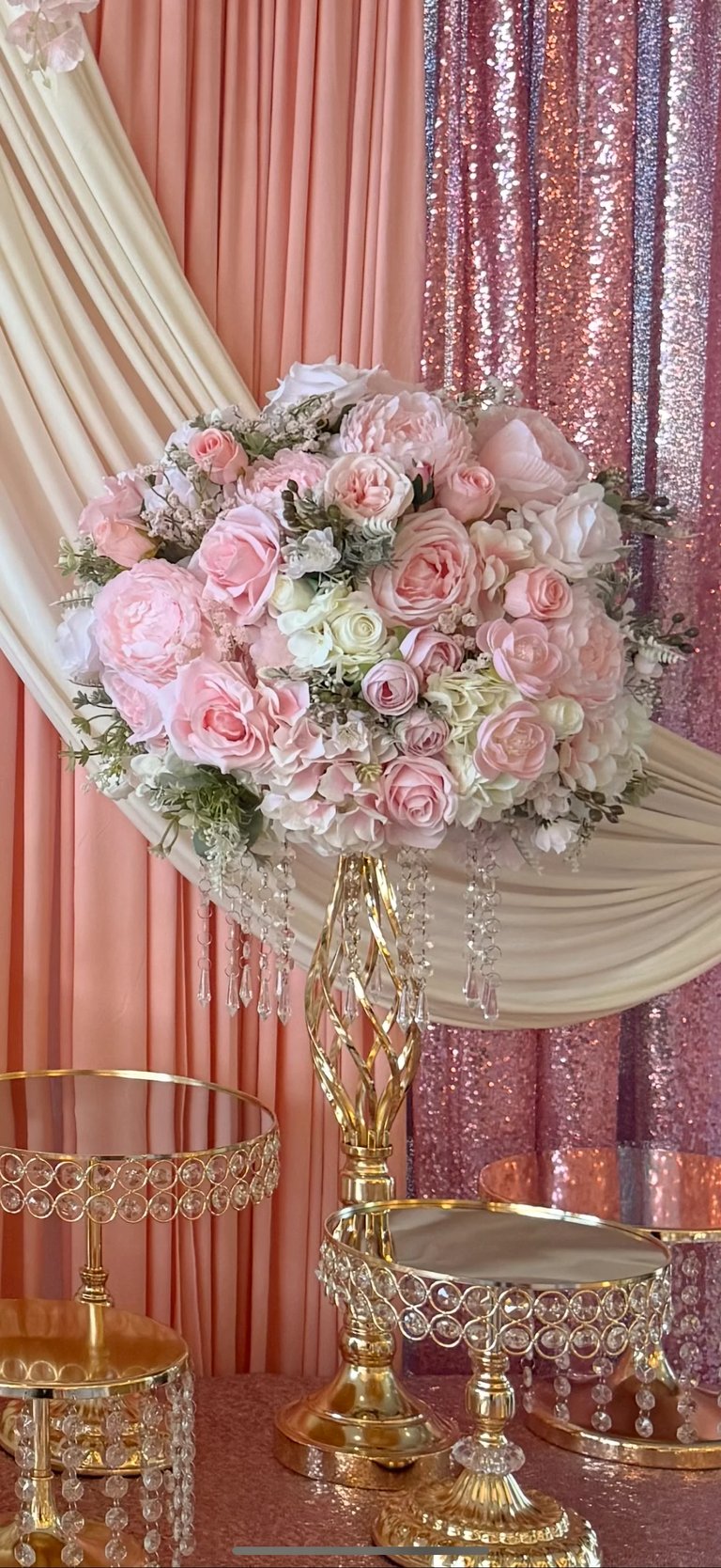 Luxurious bridal bouquet with pink and white roses on ornate gold pedestal stand against draped backdrop