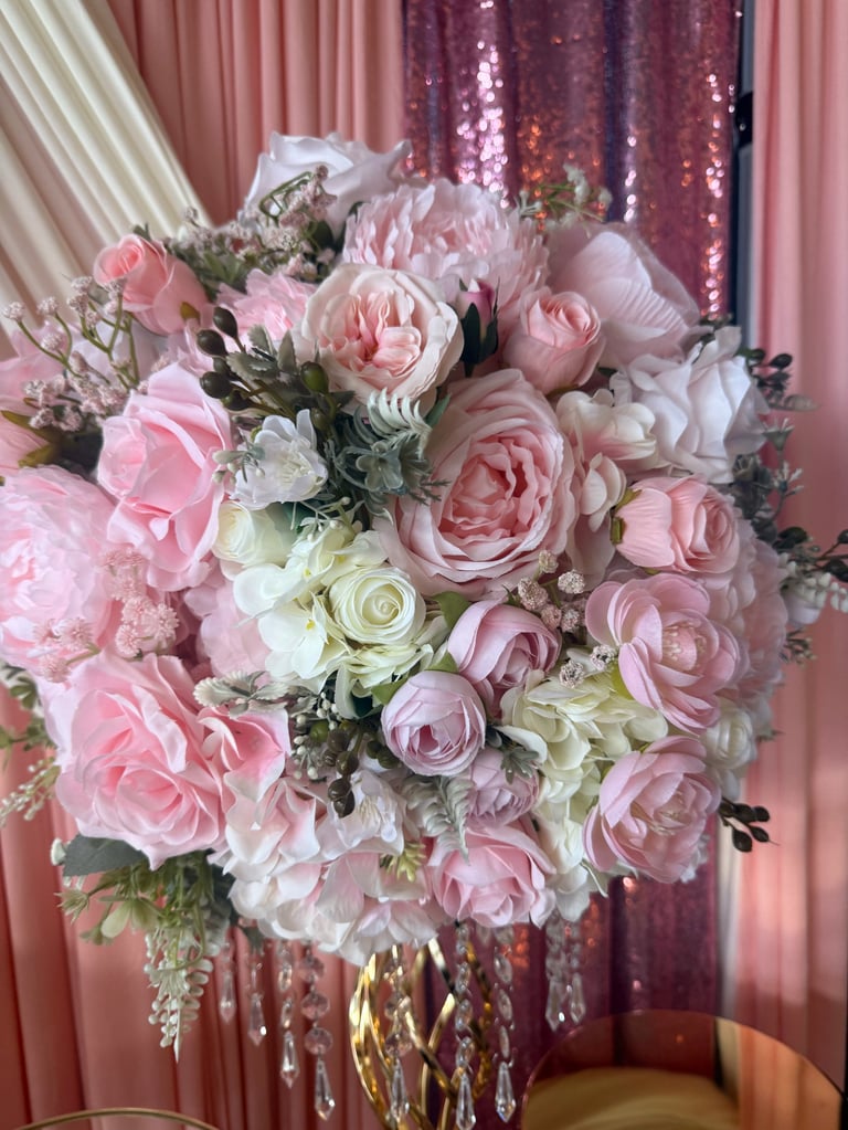 Elegant bridal bouquet with pink and white roses, peonies, and greenery with crystal beaded accents against shimmering backdrop