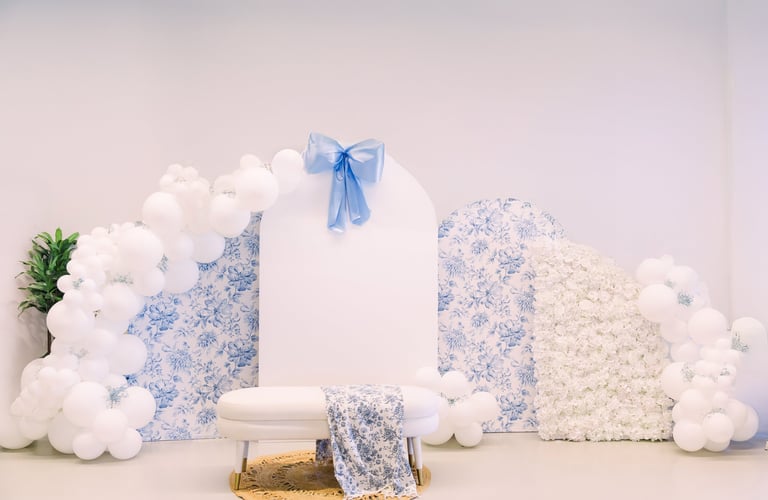 Blue and white decorative backdrop with white balloons, floral panels, white podium, blue ribbon