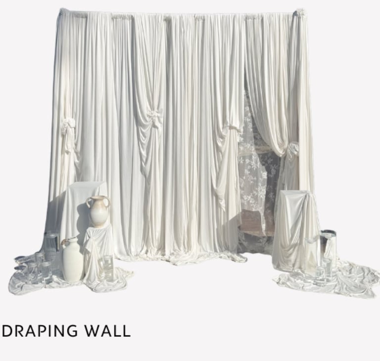 Draping wall installation with flowing white fabric curtains and decorative vessels displayed against a neutral background