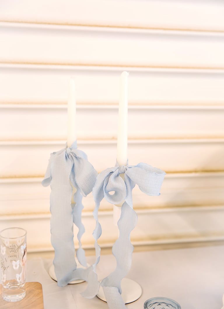 Elegant white candelabra with blue ribbons holding three white candles on a table