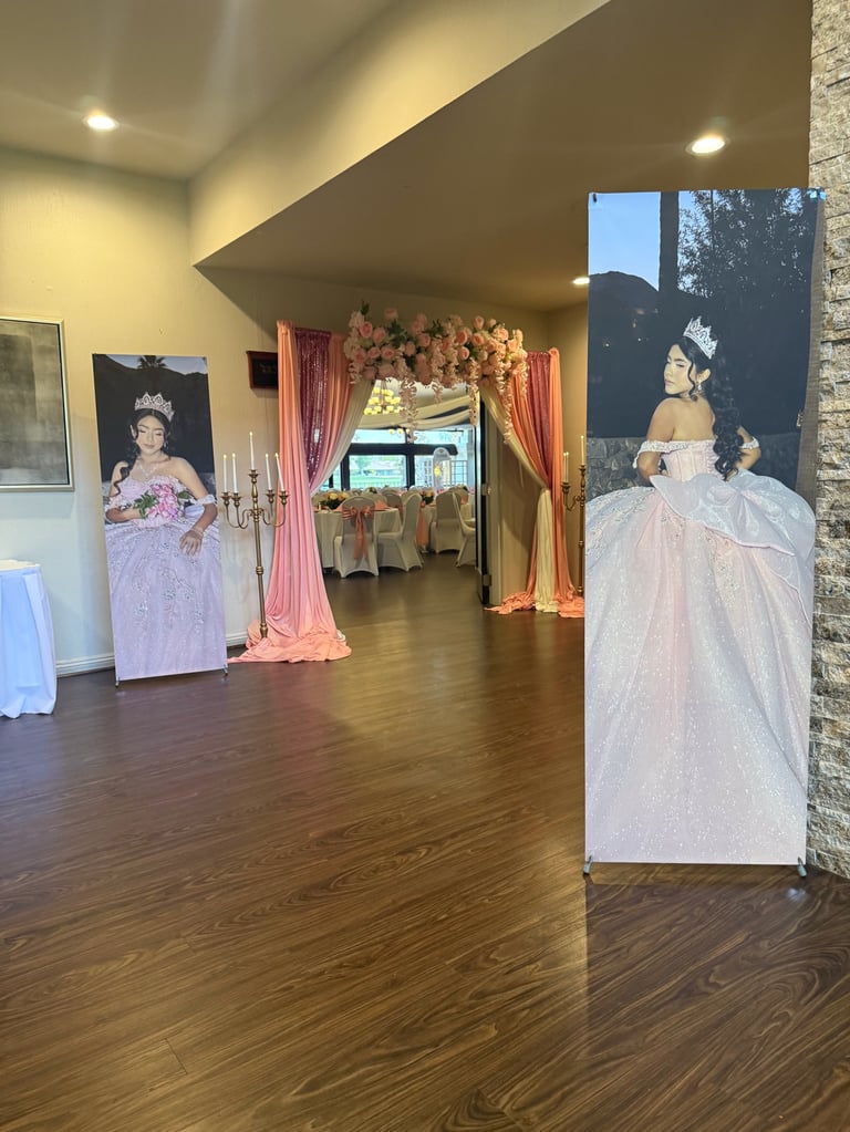 Elegant banquet hall with portrait displays of people in formal gowns, pink drapes, and dining tables in background