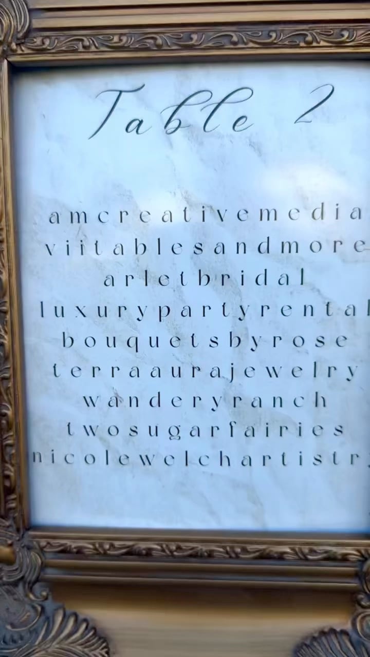 Framed sign displaying Table 2 with a list of vendor business names in elegant script handwriting