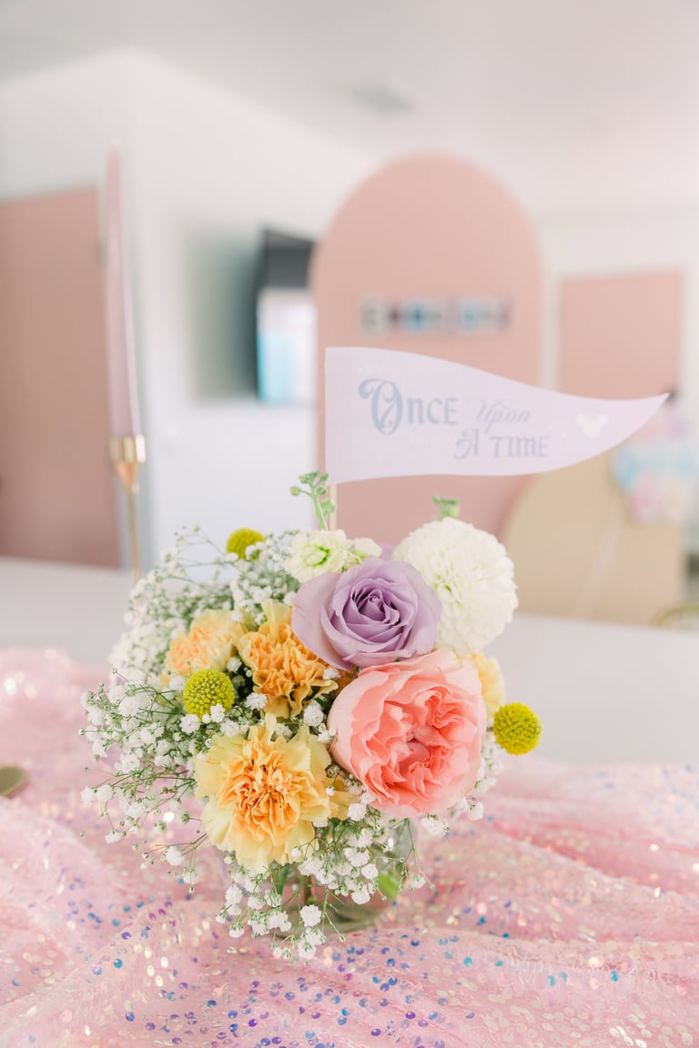 Pastel wedding centerpiece with colorful flowers and a Once Upon a Time banner on pink table setting